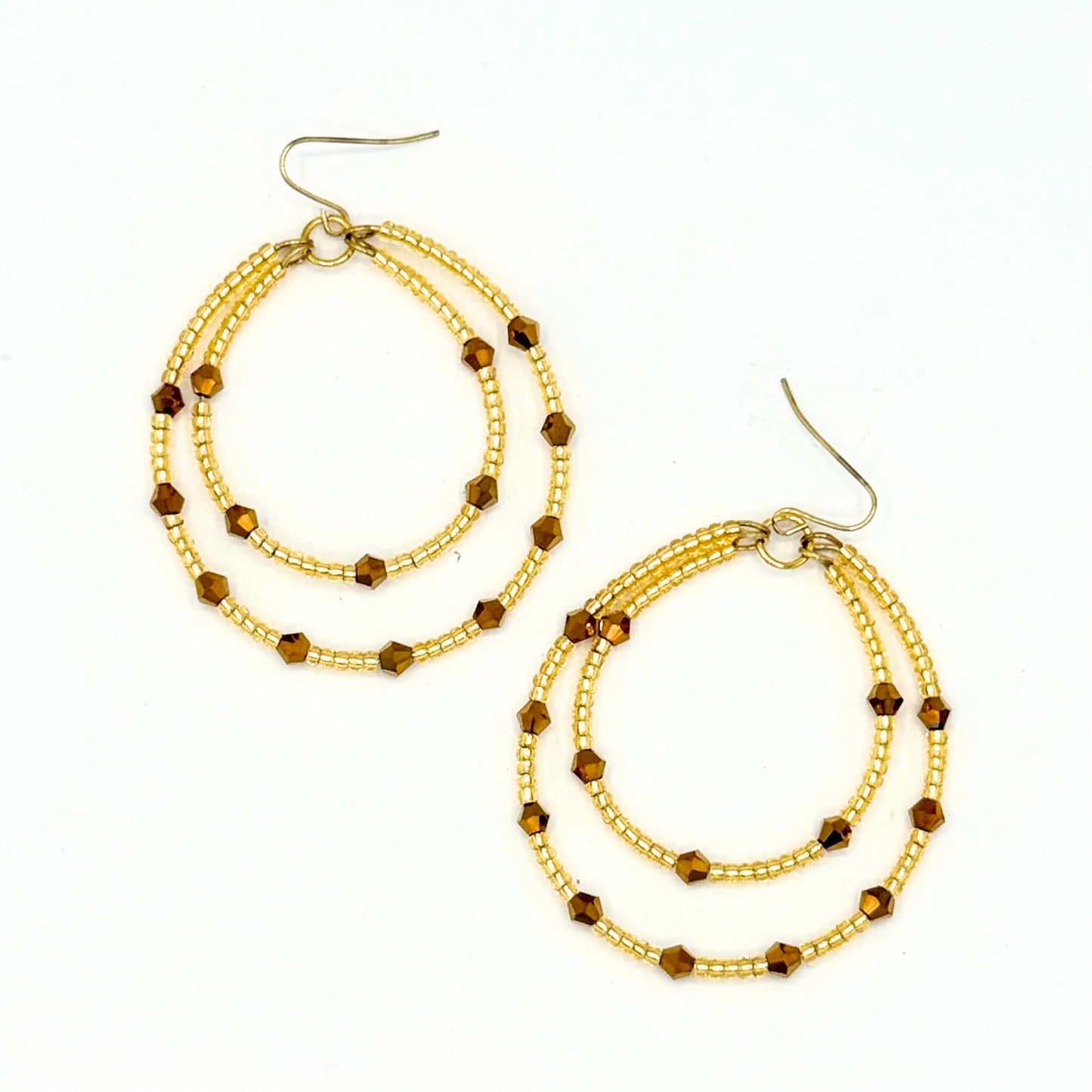 Pair of gold hoop earrings with copper beads on a white background