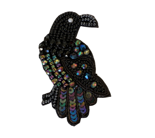 A decorative bird-shaped embellishment or brooch made with black beads and iridescent rhinestones, shown on a plain white background.
